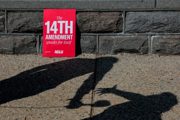 People's shadows next to a placard referencing the Fourteenth Amendment to the U.S. Constitution, during a demonstration outside the U.S. Supreme Court building as the court hears oral arguments on the legality of the Trump administration's effort to limit birthright citizenship for the children of immigrants, in Washington, D.C., U.S., April 1, 2026. REUTERS/Kylie Cooper     TPX IMAGES OF THE DAY